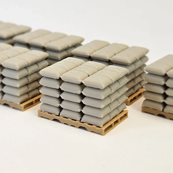 H0-Miniaturen von hellgrauen Säcken, gestapelt auf großen Frachtpaletten.